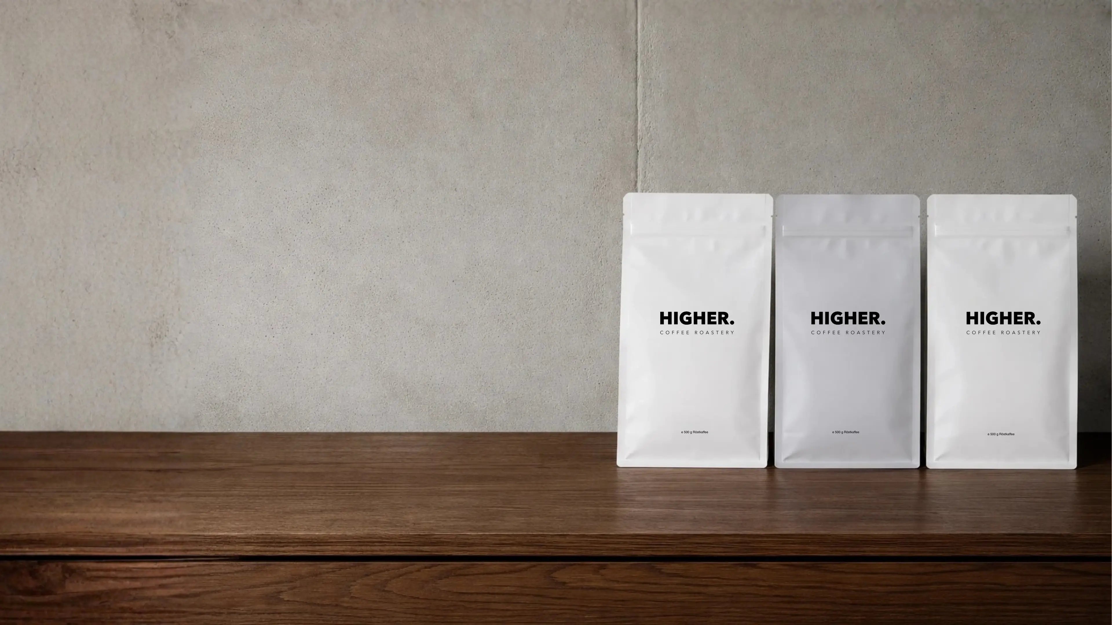 3 Kaffeeverpackungen Higher auf Holztisch 